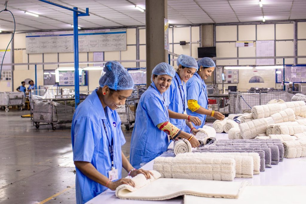 Smiling textile workers in a factory sorting and rolling fabrics.