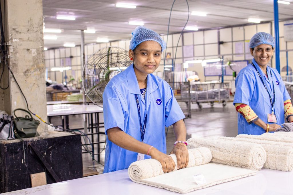 Indian textile workers folding towels in a factory setting, showcasing teamwork and craftsmanship.